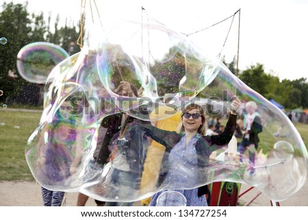BERLIN - JUN 10: Young adults are making giant soap bubbles on a summer afternoon at Mauerpark, with the flea market in the background on June 10 2012 in Berlin, Germany.
