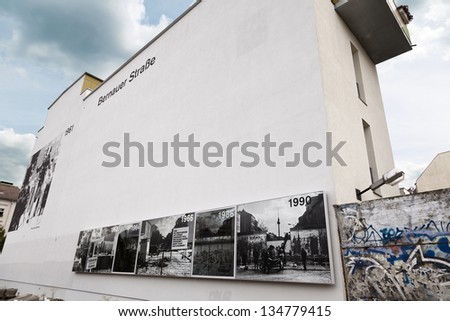 BERLIN - JUN 10: Graffiti covered remains of the Berlin wall in Bernauer strasse. Photos on the building\'s wall depict the wall all through the years  on June 10 2012 in Berlin, Germany.