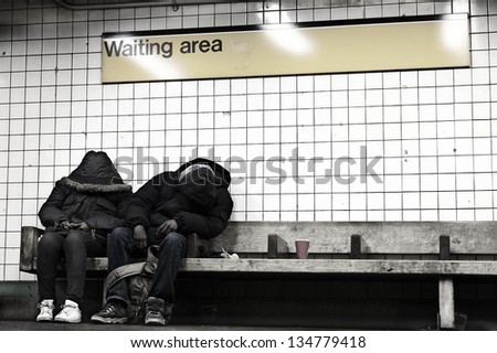 NEW YORK - NOV 14: People sitting on a bench at a subway station\'s waiting area, hidden behind their coats, on November 14 2012 in New York, New York.