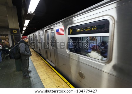 NEW YORK - NOV 6: Several commuters are standing on the 42nd street subway station R line platform, waiting for the N train to stop on November 6 2012 in New York, New York.