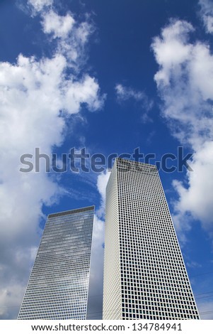 Two skyscrapers on the background of blue cloudy sky.