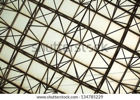 Architectural design detail - abstract geometric mesh pattern made of metal rods and somewhat dirty yellowish glass.