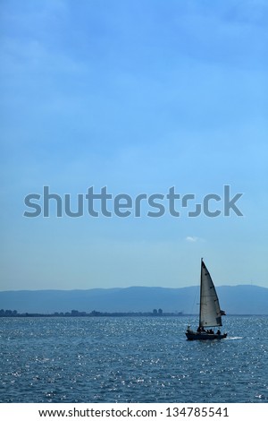 View to the south at the silhouette of a small sailboat roaming the waters of Haifa bay in Israel.
