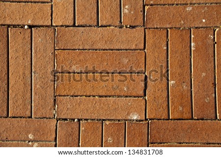 Red brick shaped floor tiles lit by direct afternoon sun. Good as background.