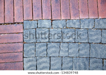 Gray floor tiles with wavy/rippled texture  and red bricks lit by diffused afternoon sun. Good as background.