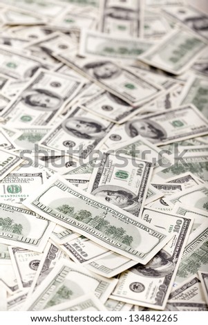 A high angle view of a very large amount of 100 US$ money notes in a bulky mess. On the front there is a note showing its reverse side, depicting the Independence Hall. Very Shallow depth of field.