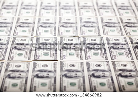A large quantity of 100 US$ money notes lined up in rows. Very shallow depth of field.