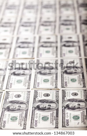A large quantity of 100 US$ money notes lined up in rows. Very shallow depth of field.