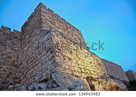 Part of the wall of the old city of Jerusalem, just before sundown with artificial light painting the wall with orange from below. An HDR photo.