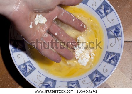 the remains of an egg shell in a plate full of its former contents, after squashed by hand