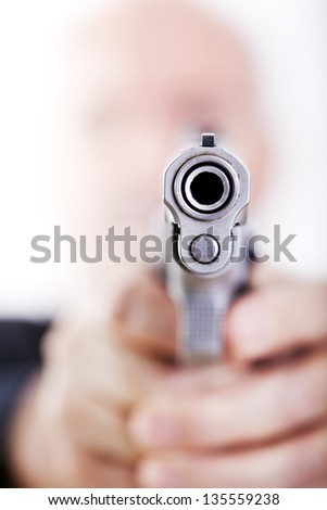 A mature adult man wearing a suit, holding a 9mm gun with both hands aiming it to the camera. Isolated on white background.