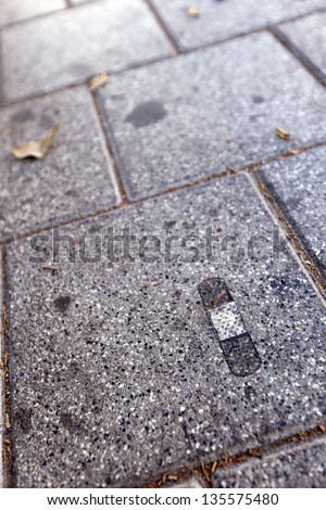 A used dirty band-aid stuck to the pavement.