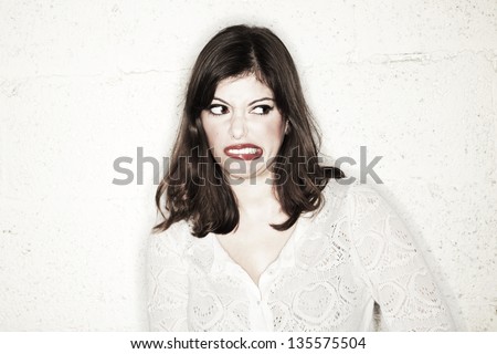 Portrait of a beautiful young woman looking to the side with an exaggerated disgusted expression, or maybe simply growling like a dog.