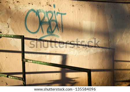 A graffiti tag 'orbit' on an urban wall. Shot in the early morning.