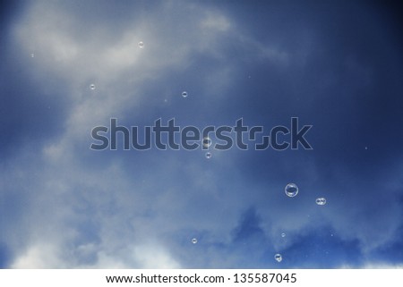 Soap sud bubbles floating in the air on the background of afternoon cloudy sky.
