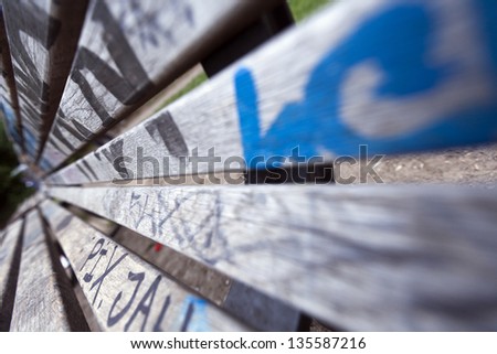 Wide angle close-up of a graffiti covered bench.