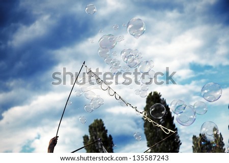 Berlin, Germany - June 10th, 2012: An anonymous man making giant soap bubbles on an early summer Sunday afternoon at Mauerpark, and a kid trying to catch the bubbles.