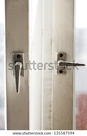 Close up view of two window handles. One of the windows is open, other one closed.