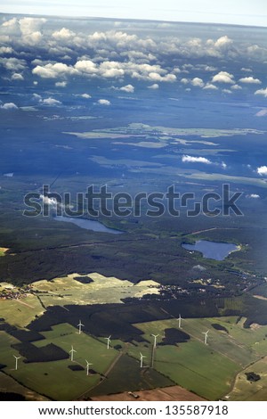 Aerial view of wind turbines amidst green land features.