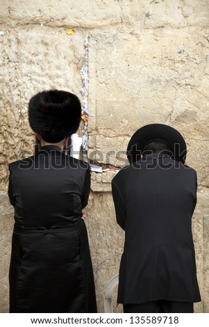 JERUSALEM - MAY 21: Two Jewish orthodox men, pressed in prayer against the wailing wall, the holiest site in Judaism on May 21 2010 in Jerusalem, Israel.