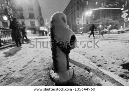 NEW YORK - NOV 7: A street in Harlem in a nocturnal snowstorm, with a snow covered fire hydrant in the front, and pedestrians blurred in the background on November 7 2012 in New York, New York.