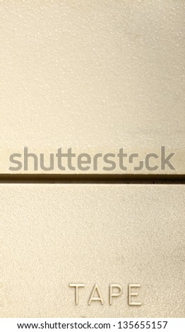 Textured yellow-beige plastic with the text \'tape\' at the bottom in relief.