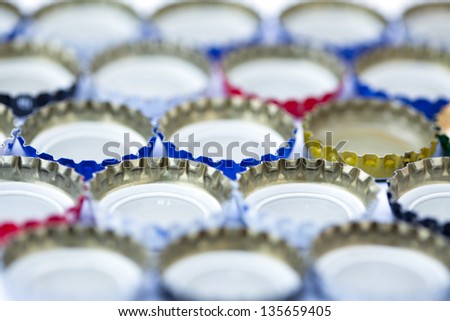 Five rows of metal bottle caps aligned upside down. Shallow depth of field.