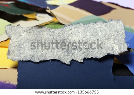 Torn long white rice fiber paper on the background of a large group of torn pieces of paper in a variety of colors. Good as copy space for text.