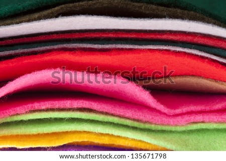 Felt fabric sheets in various colors piled up in a stack.