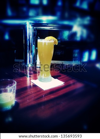 A tall glass of beer on a bar counter. Lomo-like tone and focus circular vignette create a tunnel-vision appearance, like from the point of view of a drunk person.