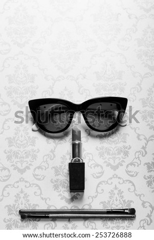 A straight face made of sunglasses, lipstick, and shadowing eyebrushes.