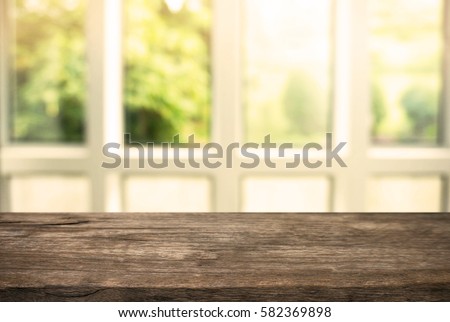 Wooden board empty table in front of blurred background. Perspective white house and  window - can be used for display or montage your products.Mock up for display of product.