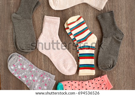 Many socks. Socks on a wooden background. Knitted socks for the cold season. Warm clothes for autumn, winter and spring. View from above. Warm clothes on a wooden background.