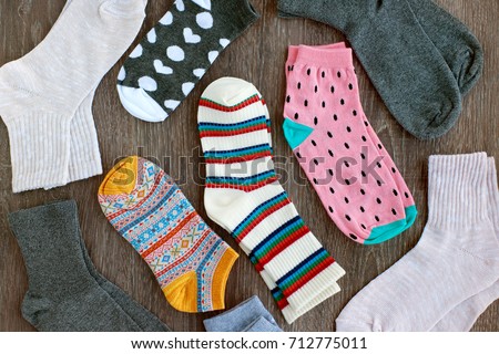 Socks of fine jersey. View from above. Many socks on a wooden background. Socks of different colors and patterns. Clothes for the cold seasons. Knitted clothing. Socks with ornament.