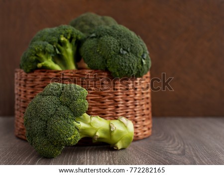 Broccoli cabbage in a wicker basket. A lot of broccoli in a wicker box on a brown background. Vintage broccoli for diet and healthy eating. Fresh raw broccoli.