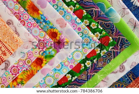 Cotton fabric is folded into an angle. Many different fabrics made of cotton. Satin, calico and cotton for sewing clothes and bed linen. Multicolored cotton fabric. View from above.
