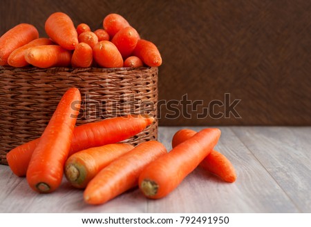 Carrots in a wicker box. A lot of carrots in a wicker basket. Carrots are stacked with a basket. Orange vegetables for diet and healthy eating. Carrots on a wooden background.