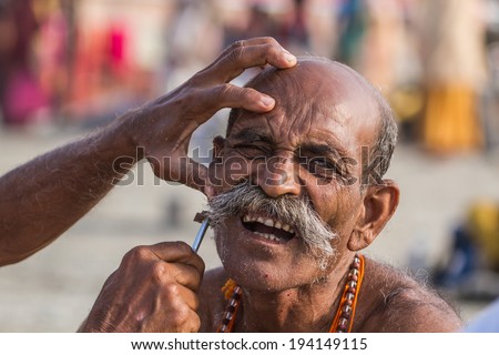 ALLAHABAD, INDIA - FEB 14 - A Hindu pilgrim has his face shaved before taking a sacred bath during the festival of Kumbha Mela on February 14th 2013 at Allahabad, India.
