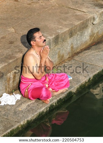 UDUPI, INDIA - Dec 7th - A South Indian brahmin prays on the steps of a sacred pond in Udupi, South India on December 7th 2008