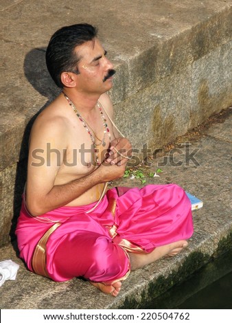 UDUPI, INDIA - Dec 7th - A South Indian brahmin silently chants mantras on the steps of a sacred pond in Udupi, South India on December 7th 2008
