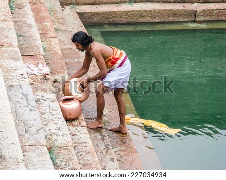MELKOTE, INDIA - MAY 9th - A priest washes the temple pots in the communal water tank on May 9th 2008 at Melkote, India.