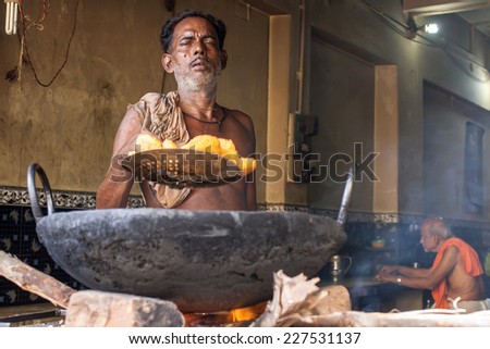 PURI, INDIA OCTOBER 9th 2010 An old man fries food in a wok in a roadside stall in East India.