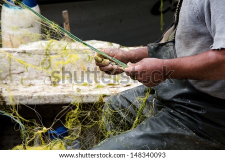 fisher cleaning his fishing net on his boat