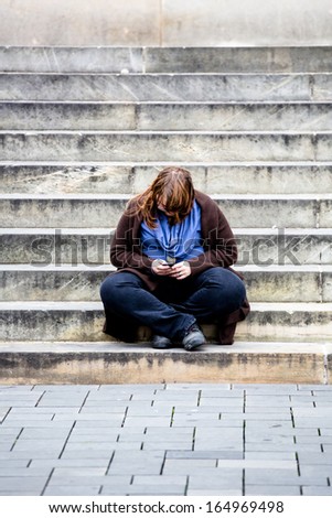 corpulent woman sitting on stairs working on her smartphone