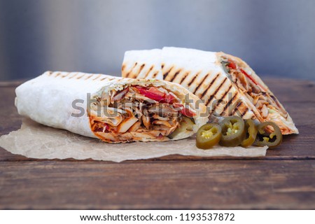 Shawarma sandwich gyro fresh roll of lavash (pita bread) chicken beef shawarma falafel RecipeTin Eatsfilled with grilled meat, mushrooms, cheese. Traditional Middle Eastern snack. On wooden background