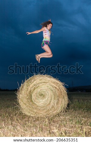 Girl jumping on a hay field