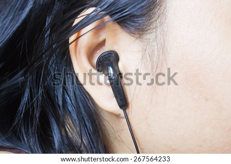 Woman ear with black earphone, Black earphone in girl\'s ear