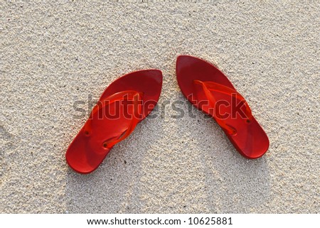 Red shoes on beach are showing the fresh red with the white sand background.