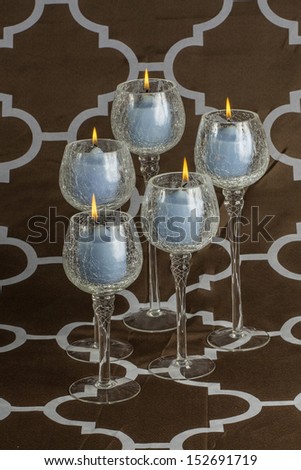Glass tea light candle holders arranged together with a brown background.