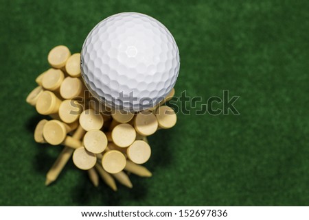 A white golf ball sitting on top of a stack of tees
